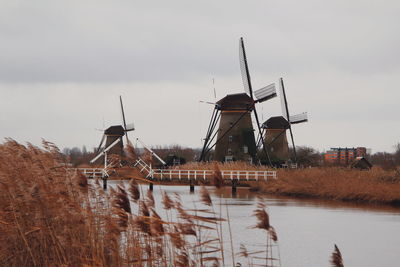 Traditional windmill in lake against sky