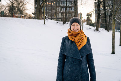 A young woman in winter clothes smiles broadly looking into the camera