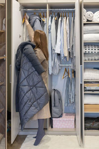 Rear view of woman holding arranging wardrobe