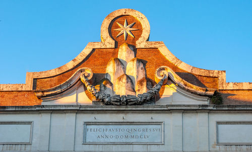 Low angle view of statue against building against clear blue sky