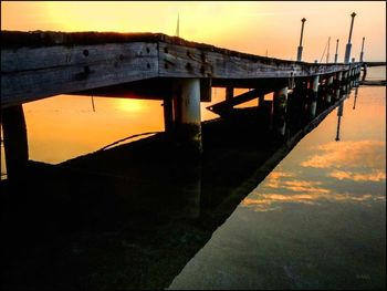 Pier in sea at sunset