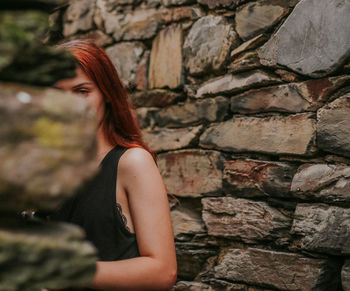 Woman standing against stone wall