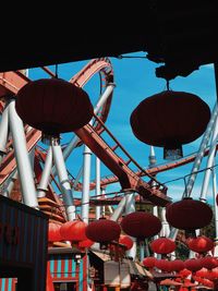 Low angle view of lanterns hanging against rollercoaster