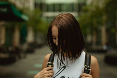 Young woman standing on footpath in city