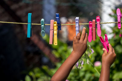 Close-up of hand holding clothespins hanging on clothesline