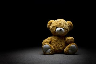 Close-up of teddy bear on floor against black background