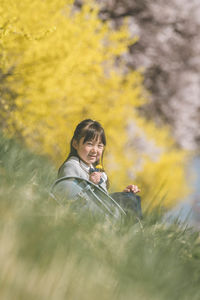 Portrait of young man using mobile phone while sitting on field