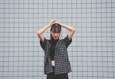 Portrait of young woman standing against wall