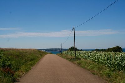 Road amidst field against sky