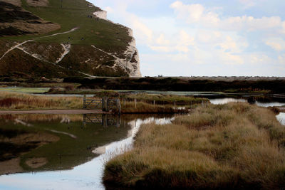 Scenic view of stream amidst agricultural landscape against sky