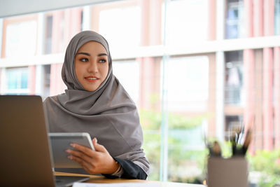 Young businesswoman wearing hijab holding digital tablet