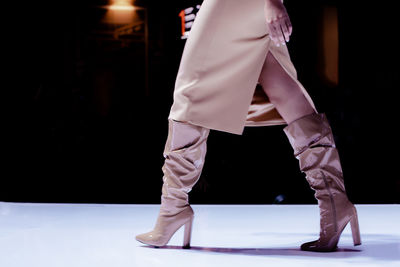 Fashion details of a beige skirt and patent leather high heel boots. women's fashion  accessories