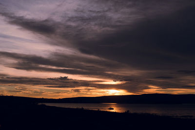 Scenic view of sea against dramatic sky during sunset