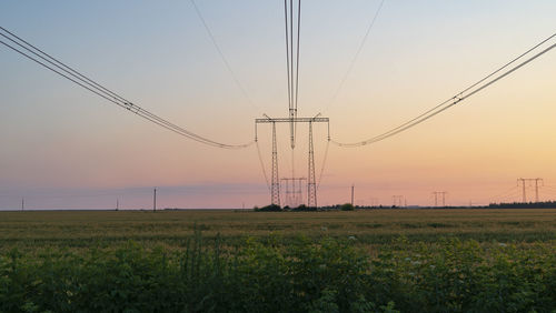 Electricity pylon on field against sky during sunset