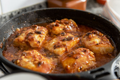 Close up of frying pan with cod and tomato sauce.