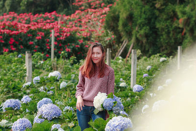 Mid adult woman standing amidst flowering plants at farm