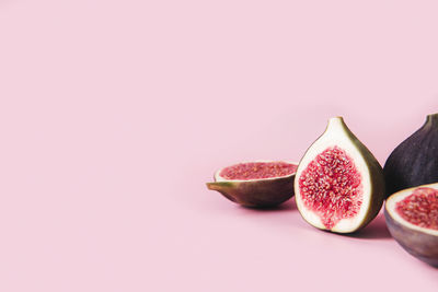 Fresh tasty fig fruit halves with shadow on pink background table with empty copy space
