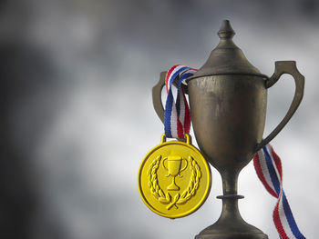 Close-up of rusty trophy and medal against sky