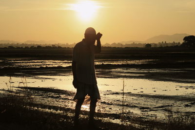 Silhouette man walking at beach against sky during sunset