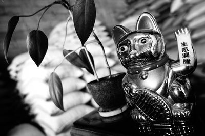 Close-up of maneki neko by potted plant on table