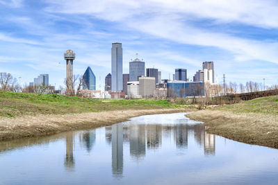 River by modern buildings against sky in city
