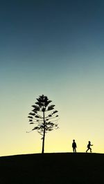 Silhouette people on field against sky during sunset