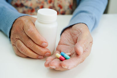 Cropped hands of doctor giving pills against white background