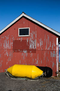 Yellow buoy by built structure against clear blue sky