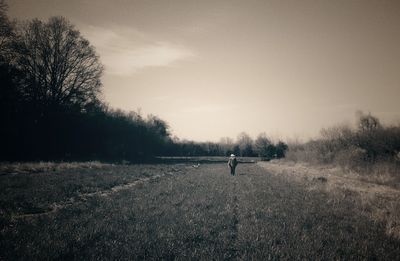 Man with dog on field against sky