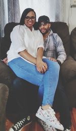 Portrait of young couple sitting on sofa