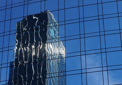 Low angle view of glass building against sky