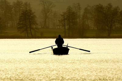 Silhouette man on boat in forest during winter