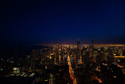 High angle view of illuminated city buildings against sky at night