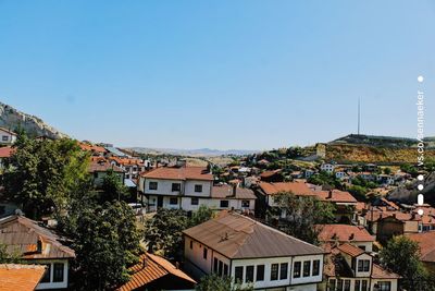 Houses in town against clear blue sky