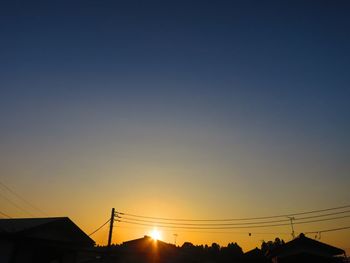 Low angle view of silhouette electricity pylon against sky during sunset