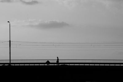 Silhouette man on bridge against sky