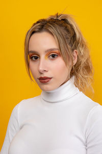 Portrait of a beautiful young woman over yellow background