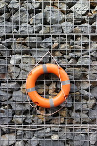 Life belt hanging on fence against heap of stones