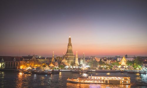 Illuminated buildings in city at sunset