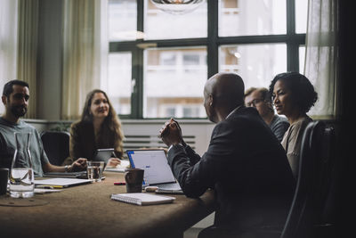 Mature entrepreneur discussing with male and female colleagues in meeting room