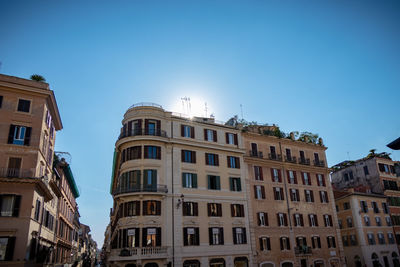 Low angle view of buildings in town against clear blue sky