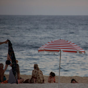 Rear view of people at beach against sky