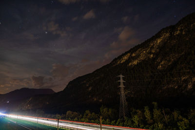 Light trails on road against sky at night