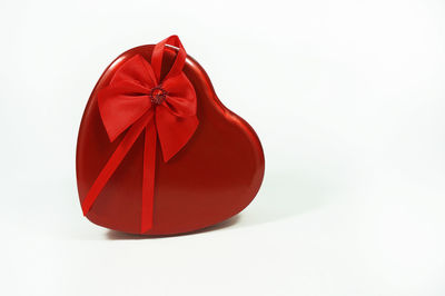 Close-up of red heart shape gift over white background