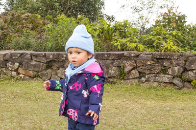 Cute boy standing on grass against trees
