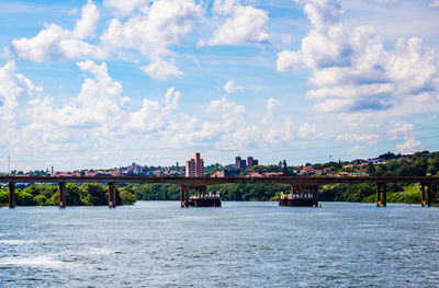 Bridge over river in city against sky