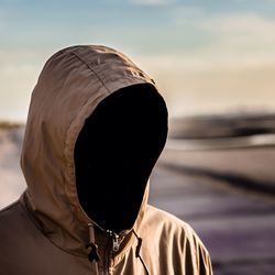 Person in hooded shirt against sky