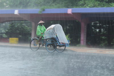 Rear view of man riding bicycle on street