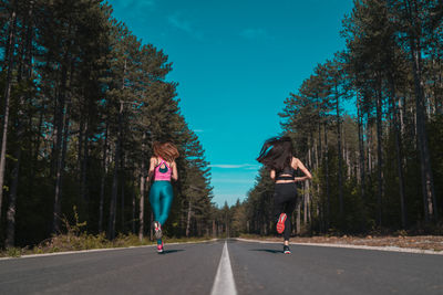 Rear view of woman running on road against trees