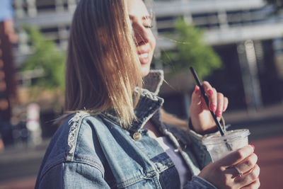 Young woman holding disposable cup in city